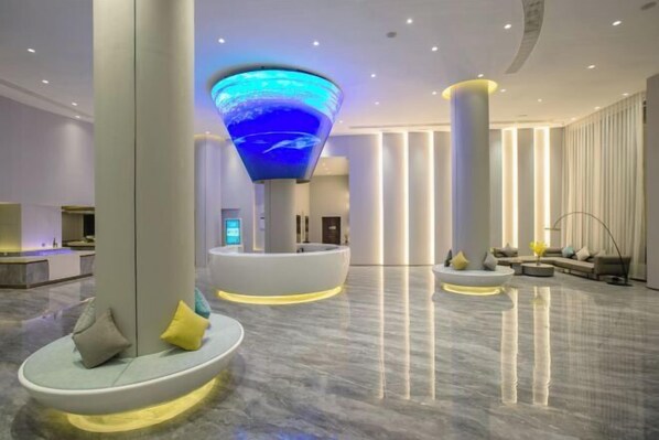 A modern lobby with a central seating area, a large illuminated sculpture, and a reception desk.