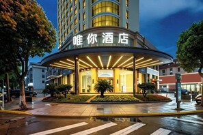 A hotel entrance with a curved facade, a well-lit entrance, and a pedestrian crossing in front. - see only hotel (Cixi)