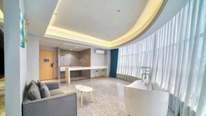 Een moderne woonkamer met een bank, een kleine tafel, een groot bad en een keuken op de achtergrond.