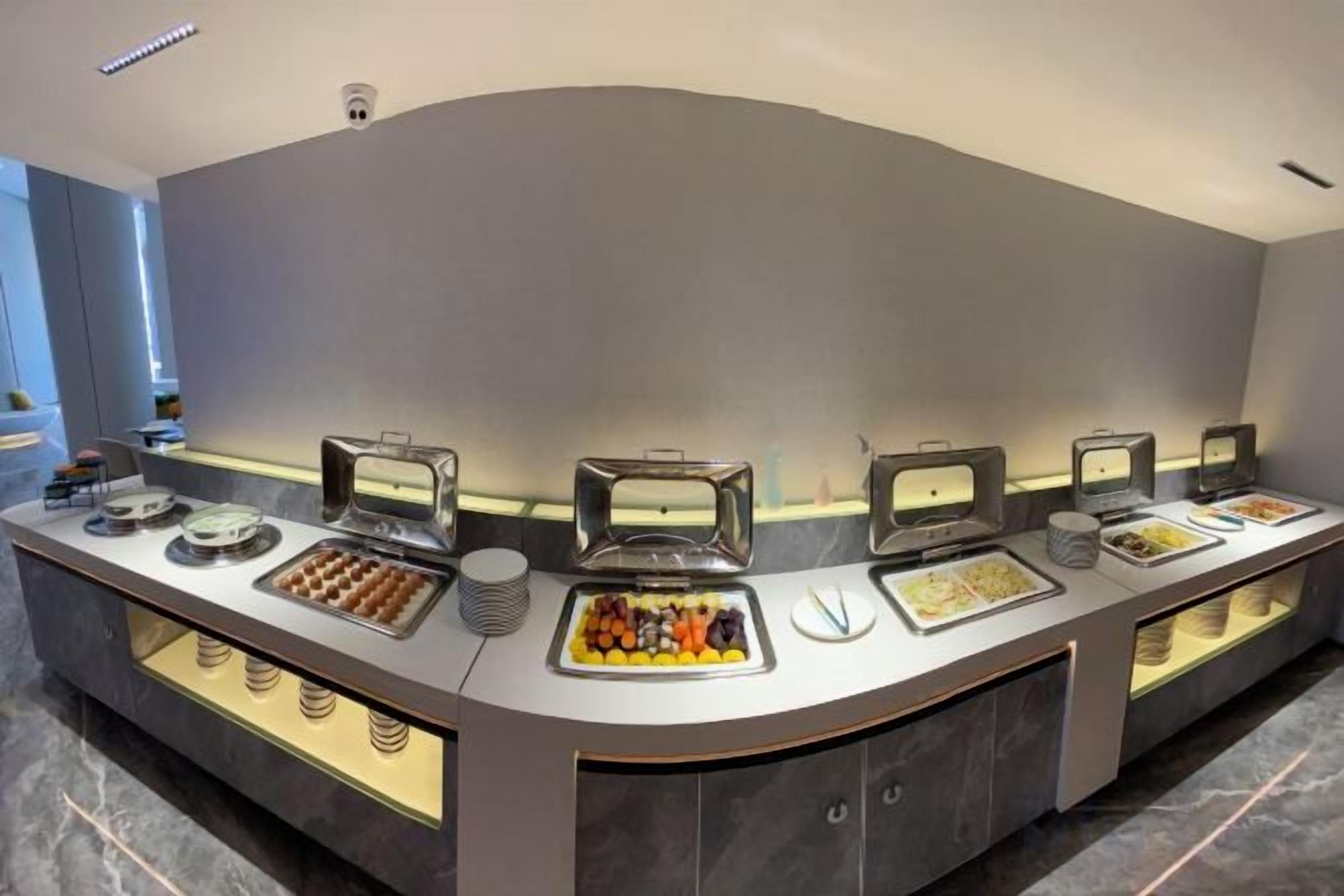 A buffet setup with multiple food stations, including a variety of hot and cold dishes, arranged on a curved counter.