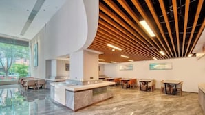 Een moderne lobby met een marmeren vloer, houten plafondlatten en een receptiebalie.