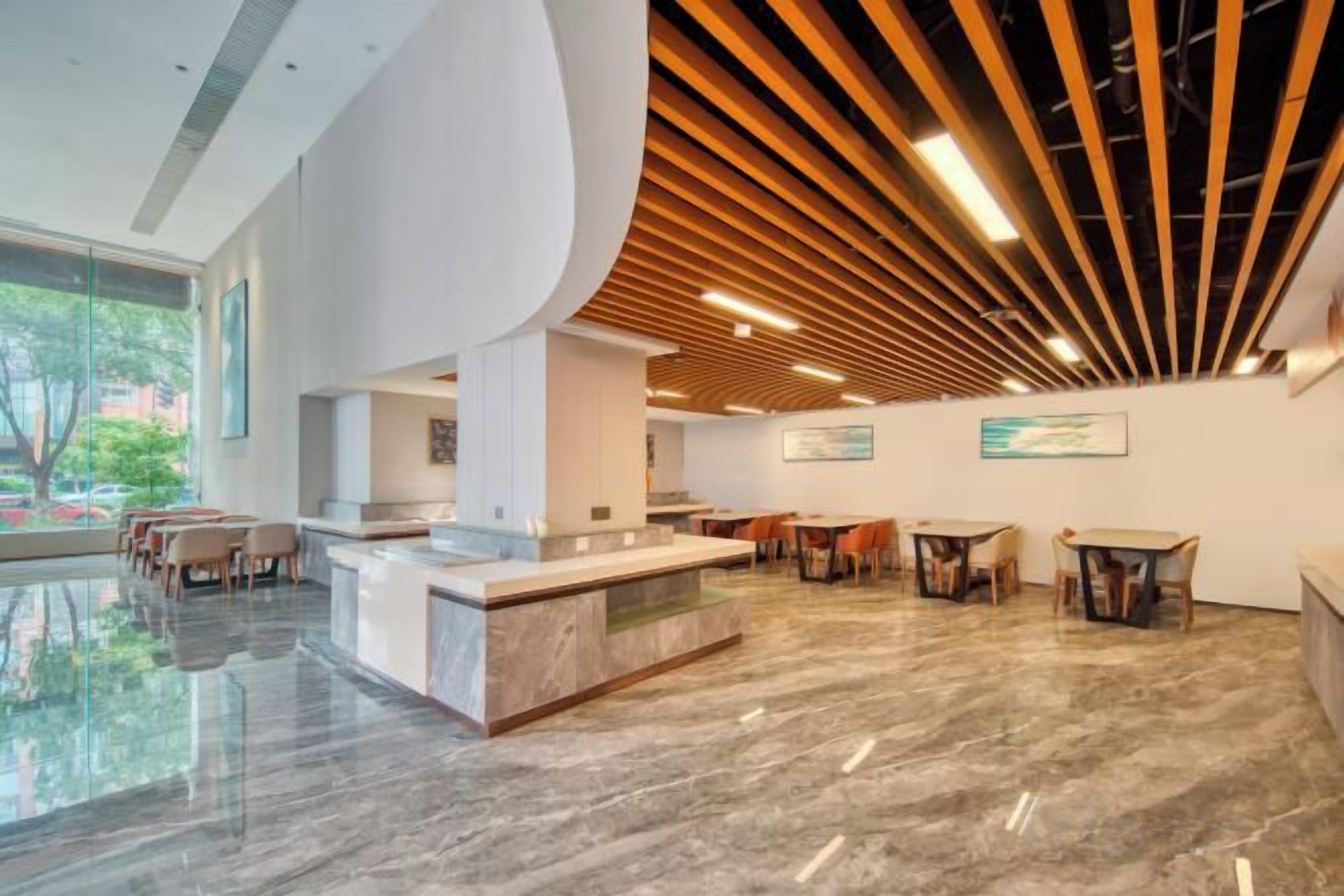 A modern lobby with a curved reception desk, seating area, and a view of the outdoors.