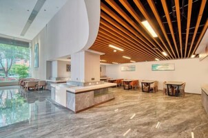 Un vestíbulo moderno con un mostrador de recepción curvo, zona de estar y vistas al exterior.
