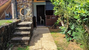 A modern house with a concrete pathway leading to a wooden staircase and a stone wall. - Sweet Dreams Bourda - Sérénité & Piscine (Cayenne)