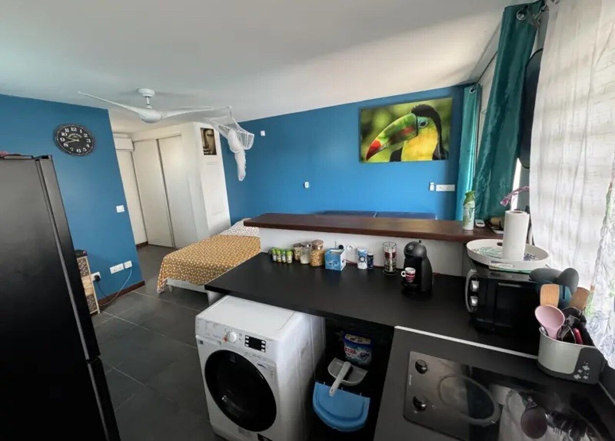 A compact kitchen with a washing machine, a coffee machine, and a small sink.