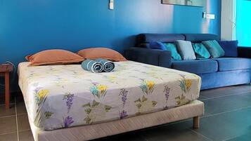 A bedroom with a bed, a sofa, and a wall-mounted artwork.