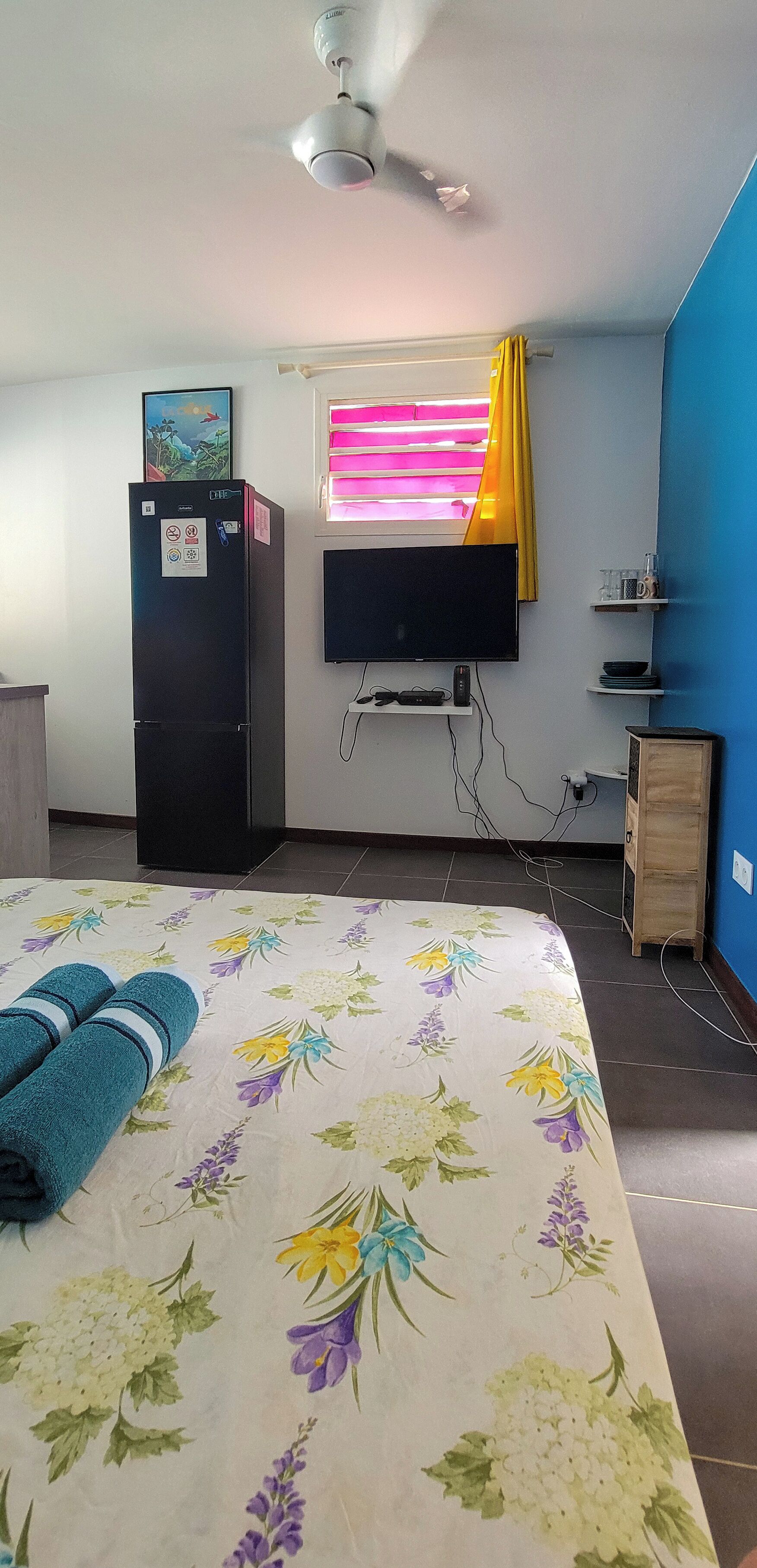 A bedroom with a bed, a TV, a wardrobe, and a window with curtains.
