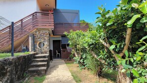 A residential property with a stone staircase leading to a wooden deck, surrounded by lush greenery and a clear blue sky. - Sweet Dreams Bourda - Sérénité & Piscine (Cayenne)