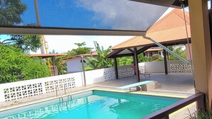 A swimming pool with a clear blue water, surrounded by a tiled deck and potted plants. - Sweet Dreams Bourda - Sérénité & Piscine (Cayenne)