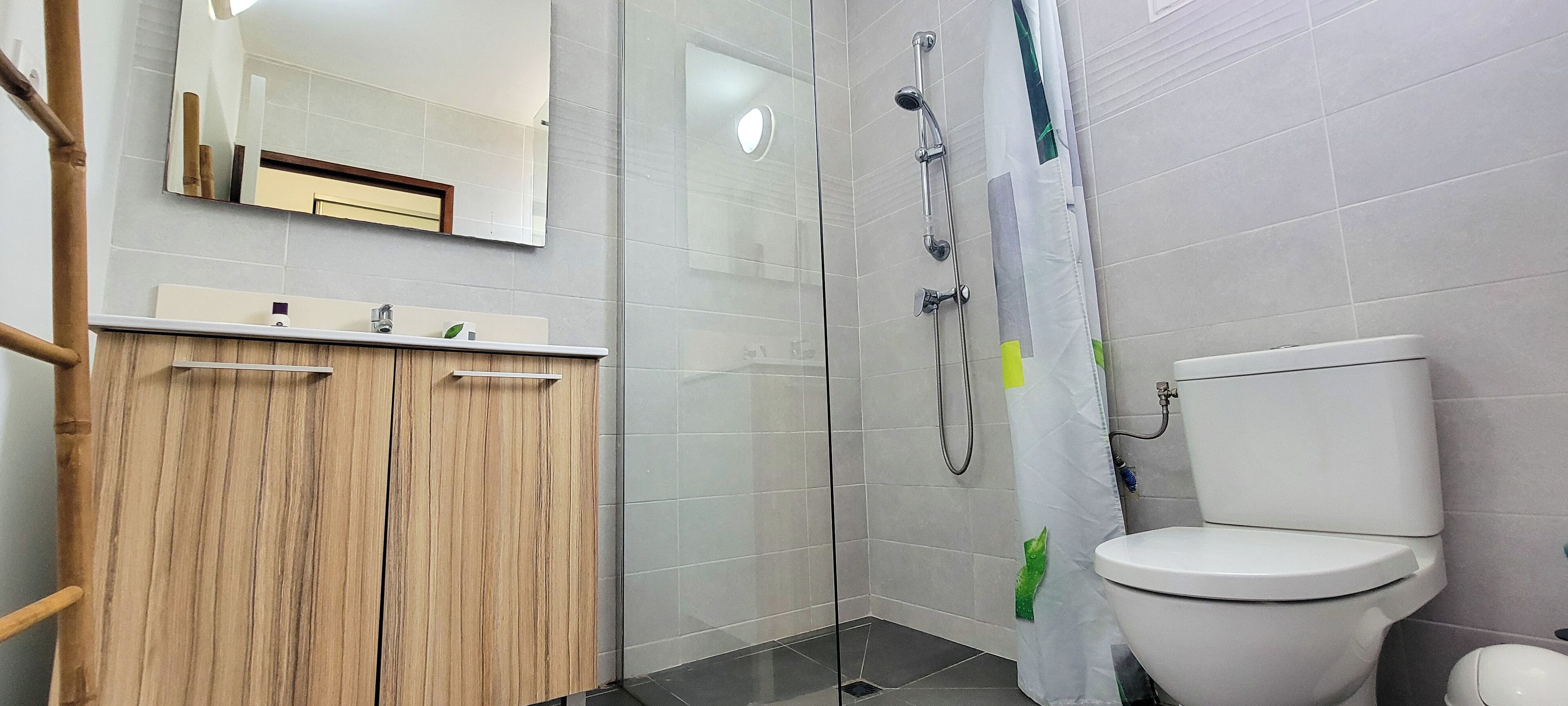 A bathroom with a wooden vanity, a shower enclosure, and a toilet.