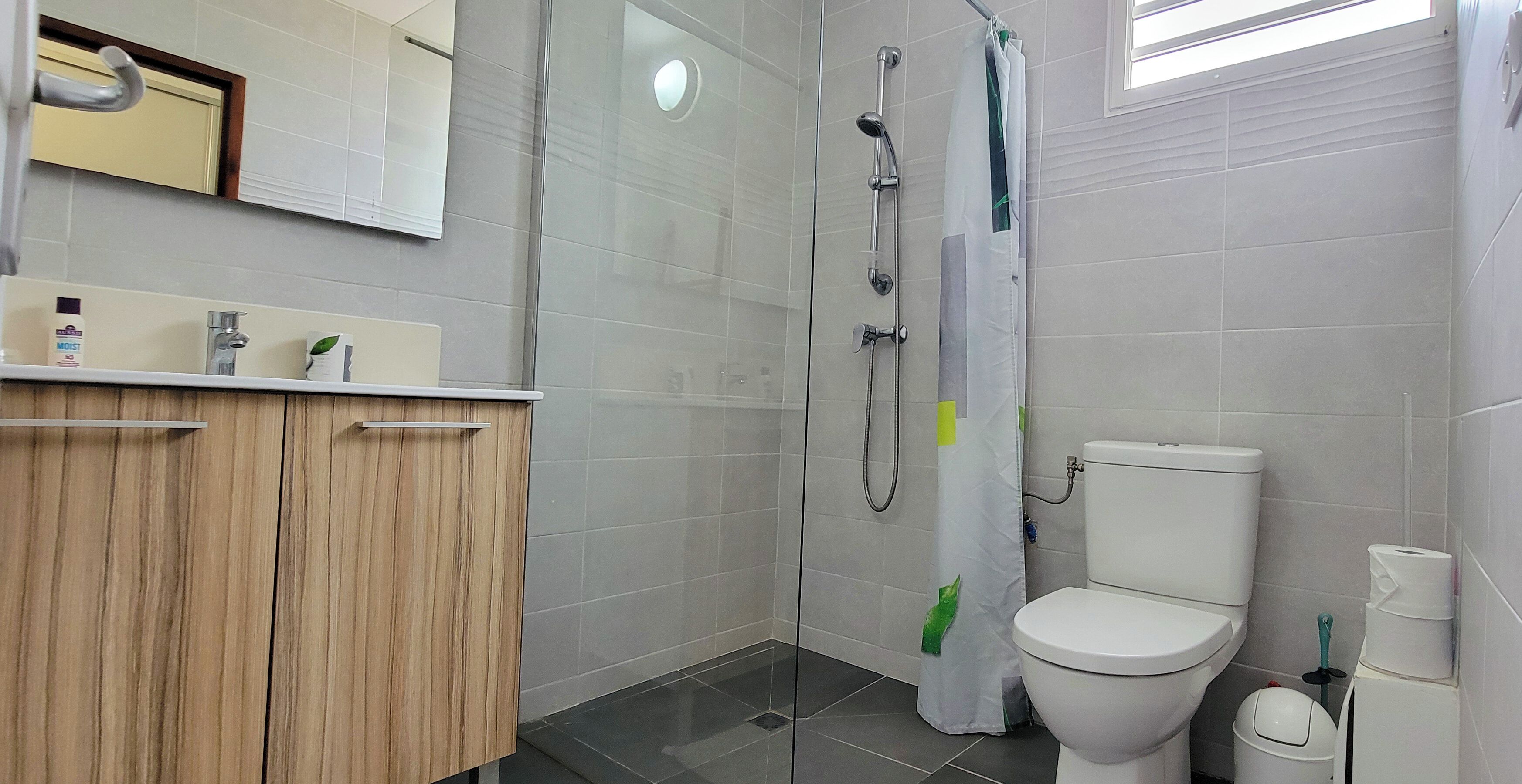 A modern bathroom with a shower, toilet, and vanity.