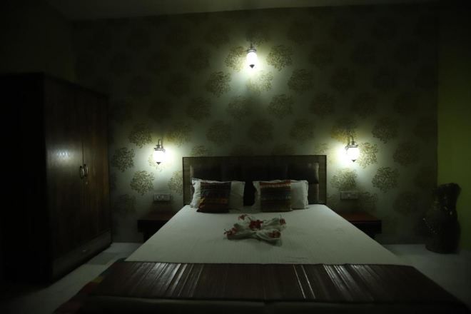 A dimly lit bedroom with a large bed, two bedside tables, and a wardrobe.