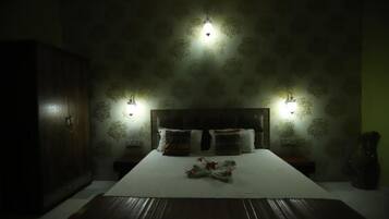 A dimly lit bedroom with a large bed, two bedside tables, and a wardrobe.