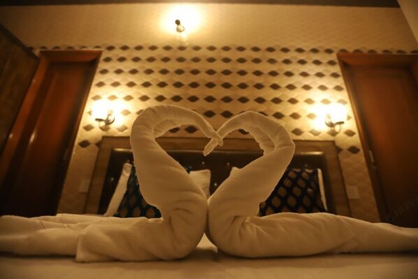 A room with a patterned wall and a heart-shaped towel arrangement.