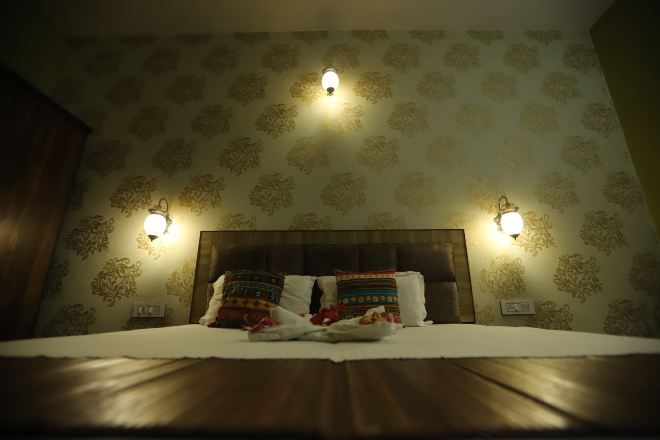 A neatly made bed with patterned pillows, a wooden headboard, and wall-mounted lamps.