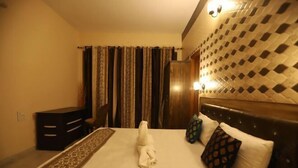 A hotel room with a neatly made bed, a desk, and a patterned headboard.