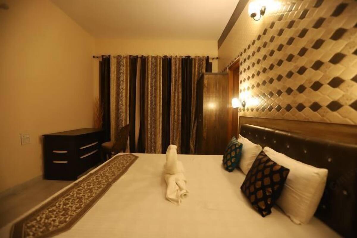 Ein Hotelzimmer mit einem ordentlich bezogenen Bett, einem Schreibtisch und einem gemusterten Kopfteil.