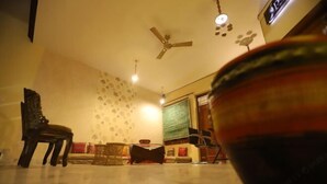 A room with a ceiling fan, a sofa, a chair, and a table.