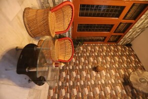 Un sol carrelé orné d’un motif, une chaise en osier rehaussée de touches de rouge et une porte en bois dotée de panneaux de verre.