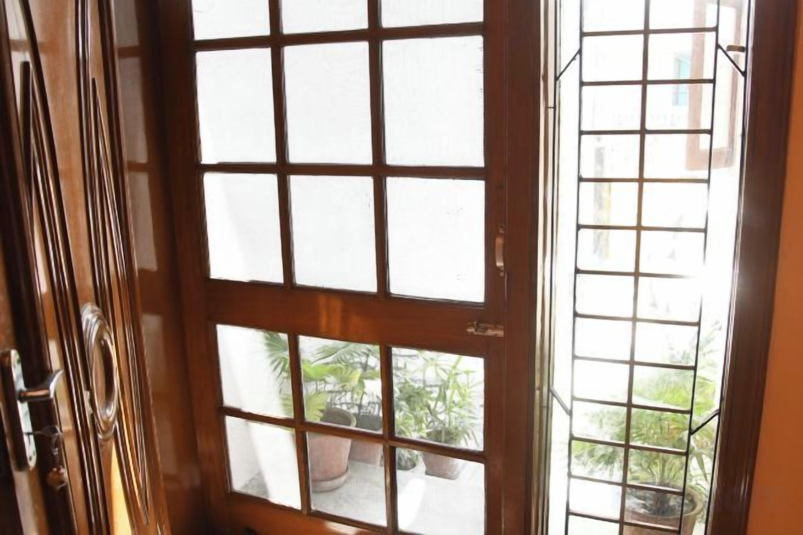 A wooden door with a grid pattern, leading to an outdoor area with potted plants.