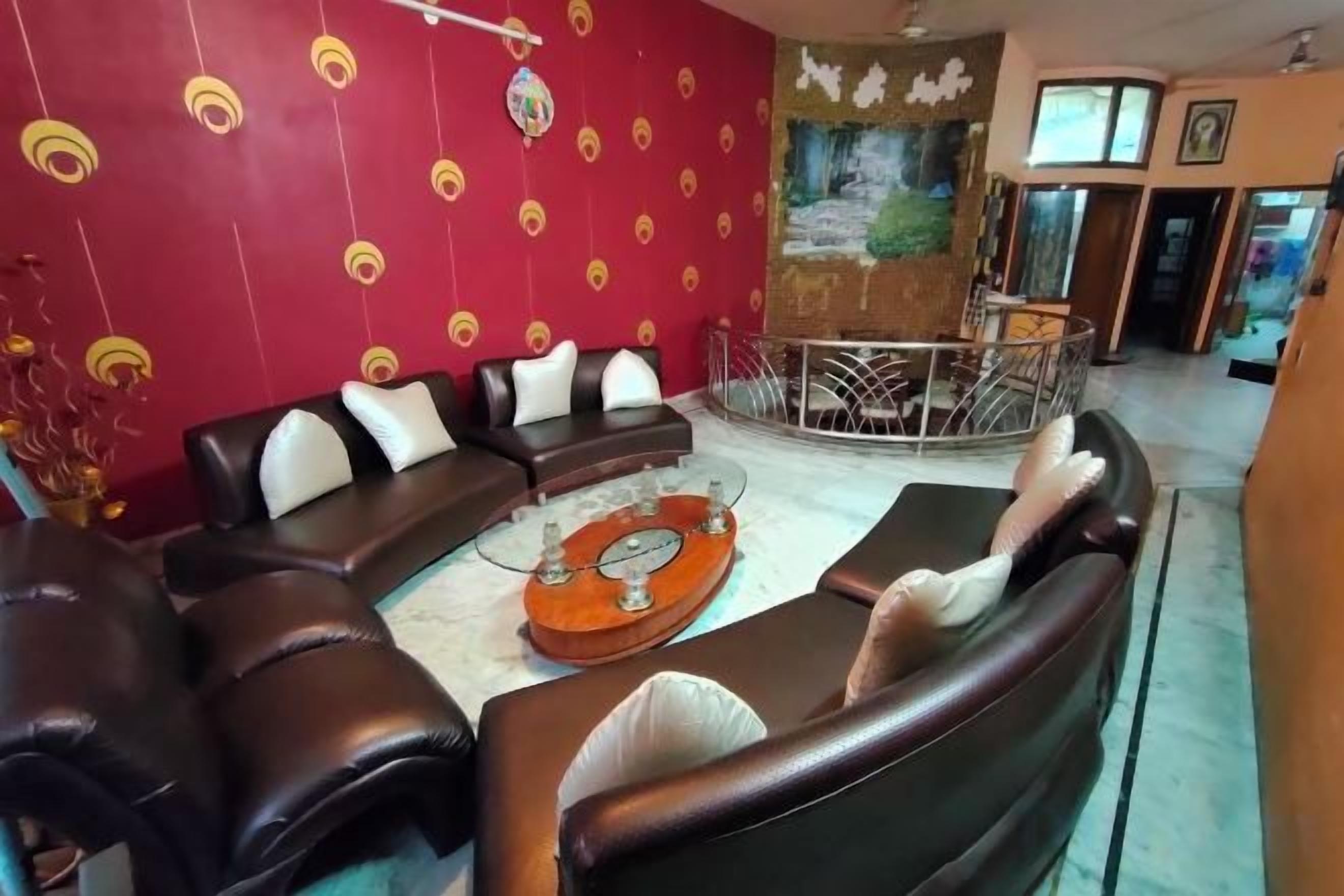 A living room with a sectional sofa, a coffee table, and a red patterned wall.