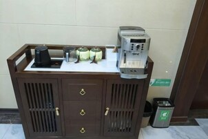 Una estación de café con cafetera, tazas y recipientes para condimentos.