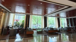 Un vestíbulo amplio con muebles modernos, ventanas grandes y piso pulido.
