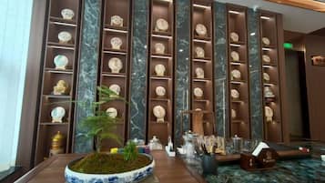 A reception area with a reception desk, a potted plant, and a wall of decorative plates.