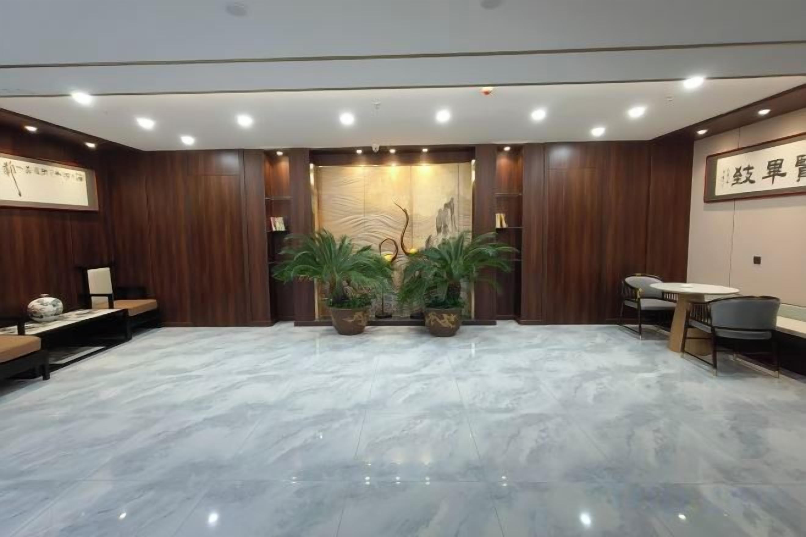 A modern hotel lobby with a marble floor, wooden paneling, a reception desk, seating area, and potted plants.