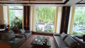 Una sala de estar moderna con sofás de cuero, una mesa de centro de vidrio y ventanas grandes con cortinas.