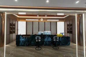 A reception area with a marble counter, two bar stools, and a modern lighting design. - Yue Cheng Commercial Hotel (Anping)