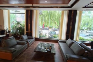 A hotel lobby with a sofa set, a coffee table, and large windows with curtains. - Yue Cheng Commercial Hotel (Anping)