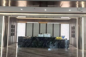 A reception area with a marble counter, a reception desk, and a wall-mounted information board. - Yue Cheng Commercial Hotel (Anping)