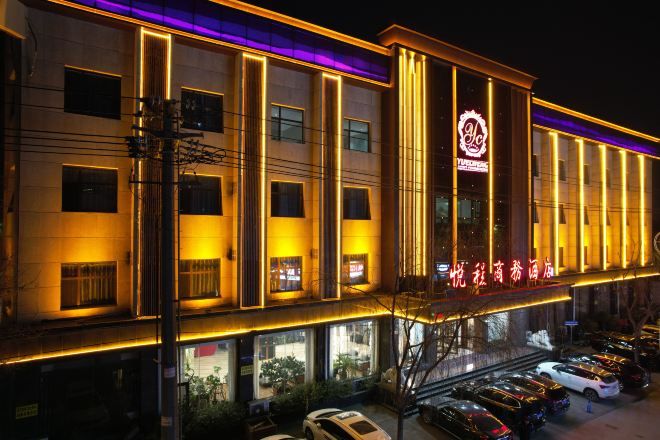 A hotel with multiple floors, a prominent entrance, and a parking area with several cars.