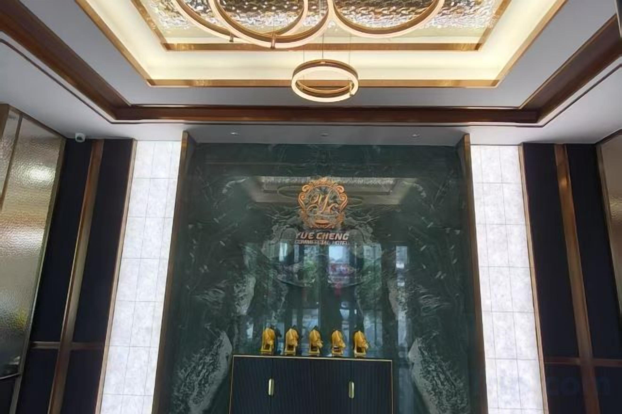 A reception area with a marble wall, a chandelier, and a sign reading 'YUE CHENG'.
