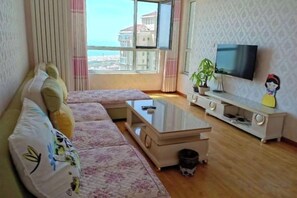 Un salon avec un canapé, un téléviseur et une vue sur la ville.