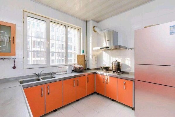 Eine Küche mit orangenen Schränken, einer doppelten Spüle und einem Kühlschrank.