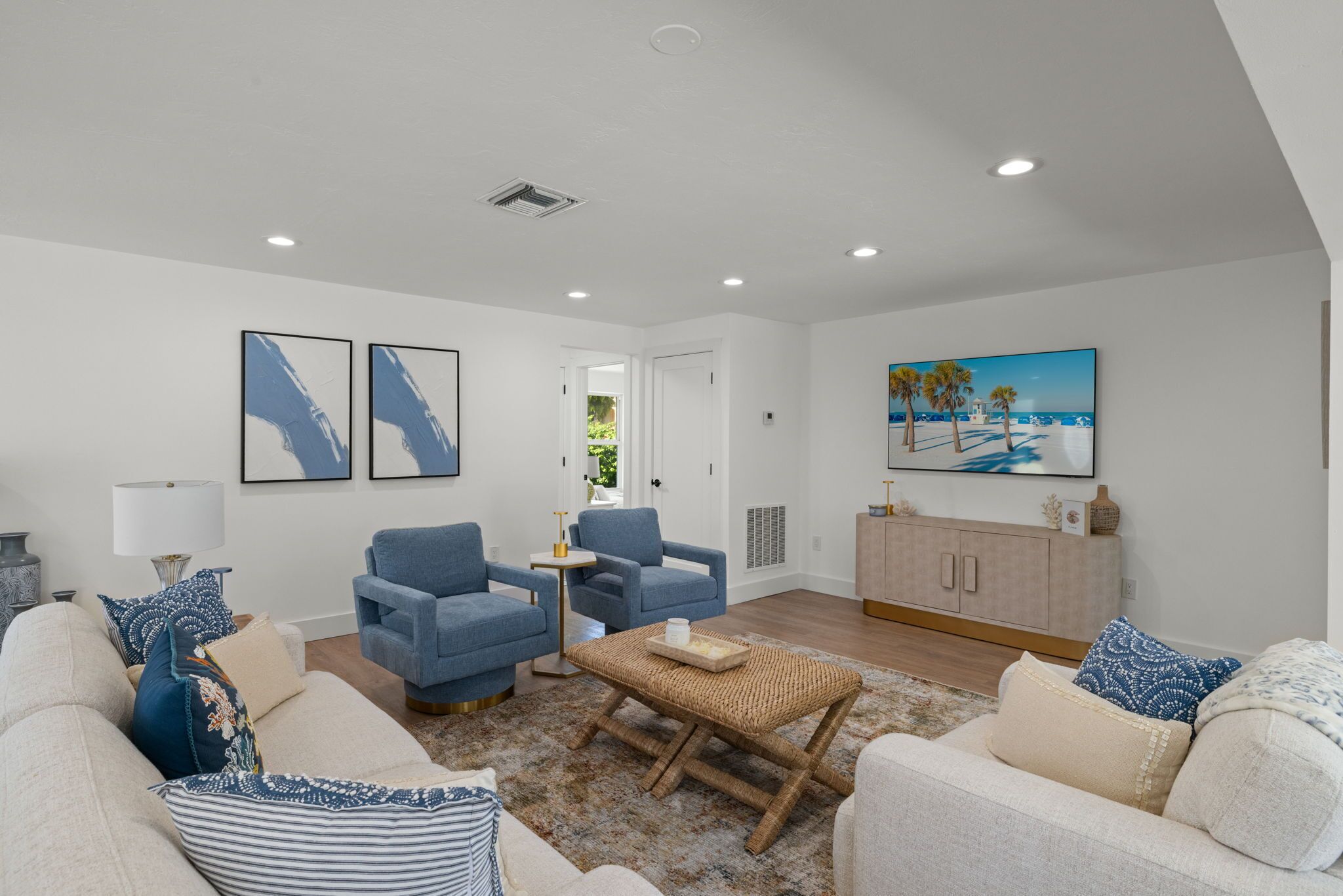 A modern living room with a sofa, two armchairs, a coffee table, and a painting on the wall.