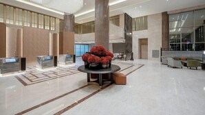 Un vestíbulo amplio con una recepción, una columna grande y una decoración central.