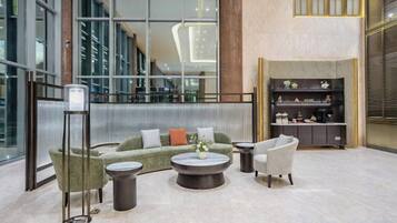 A modern lobby with a sectional sofa, armchairs, a coffee table, and a bookshelf.
