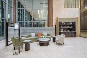 A modern lobby with a sectional sofa, armchairs, a coffee table, and a bookshelf. - Madison Hotel Huangshan Scenic Area North Gate (Huangshan City)