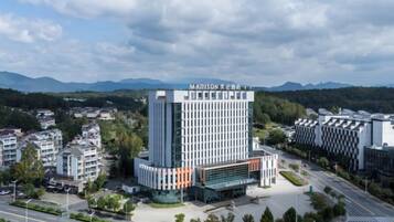 A modern hotel with a prominent central tower, surrounded by smaller buildings and a road.