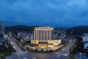 A hotel with a prominent sign, multiple floors, and a surrounding urban landscape. - Madison Hotel Huangshan Scenic Area North Gate (Huangshan City)