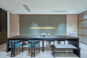 A modern dining area with a long table, bar stools, and a bench. - Madison Hotel Huangshan Scenic Area North Gate (Huangshan City)
