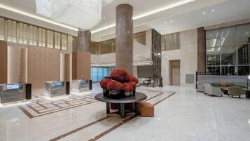 A spacious lobby with a central column, seating area, and a chandelier.