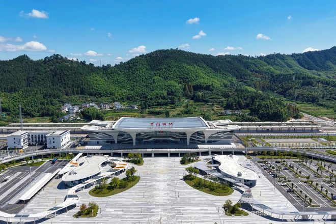 A modern airport terminal with a large, curved roof and multiple parking areas.