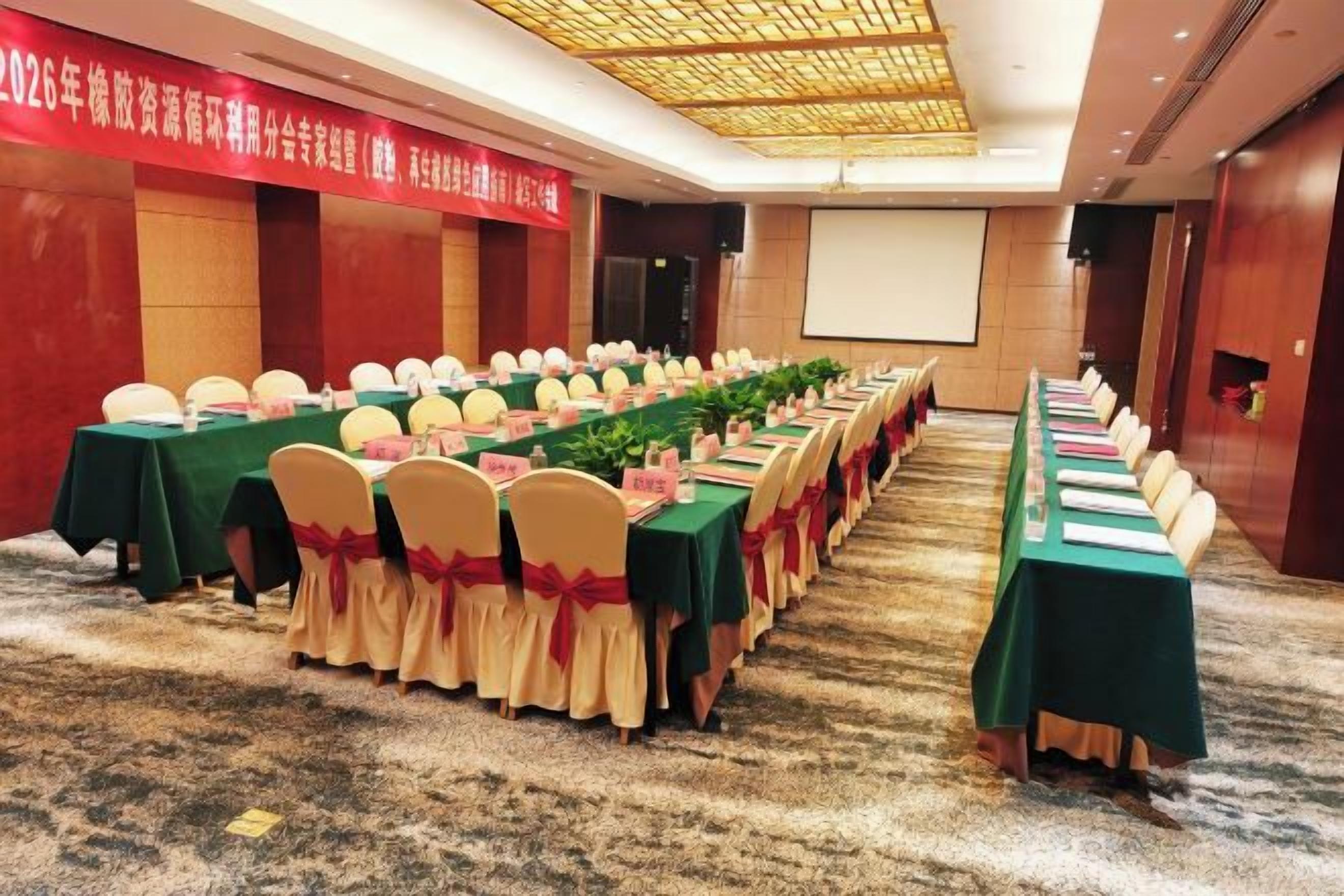 A conference room with long tables, chairs, and a projector screen.
