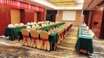 A conference room with long tables, chairs, and a projector screen.