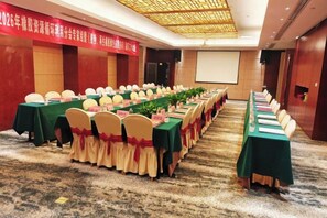 Une salle de conférence équipée de longues tables, de chaises et d’un écran de projection.