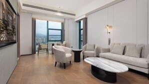 Una sala de estar moderna con un sofá, sillones, una mesa de centro y vistas amplias a través de un gran ventanal.